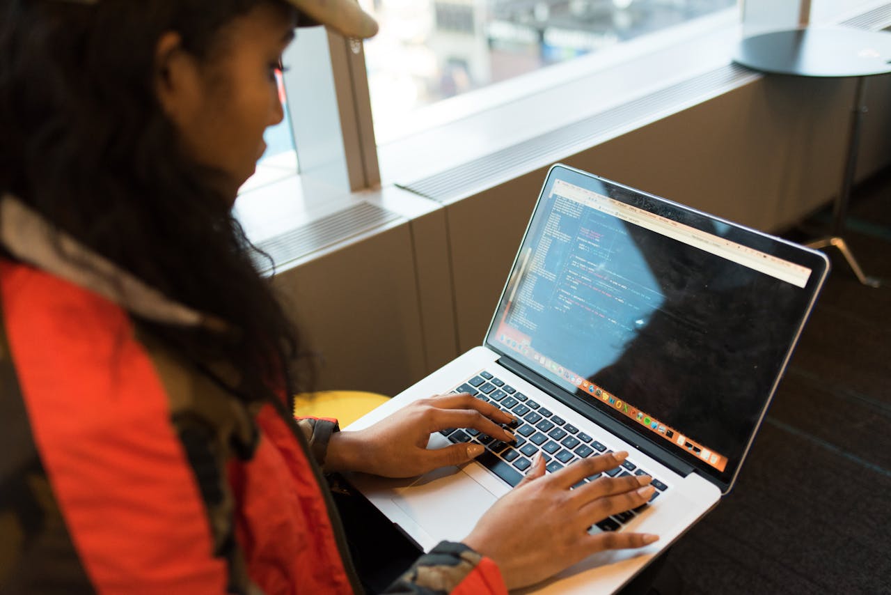 Services A focused woman typing code on her laptop indoors, embodying tech innovation.