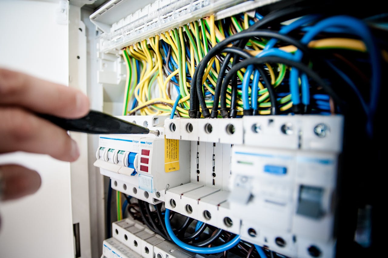 Mastering the First Impression: Your intriguing post title goes here Hand of electrician working on a circuit breaker panel with colorful wires, ensuring safe electrical connections.
