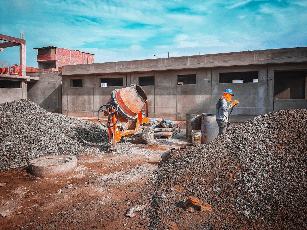 Crafting Captivating Headlines: Your awesome post title goes here A construction site with a worker wearing safety gear next to a cement mixer and gravel piles.